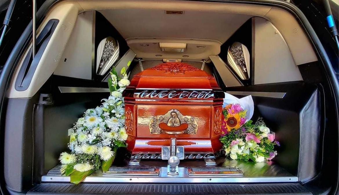 Ataúd a bordo de la unidad de traslado, acompañado de arreglos florales