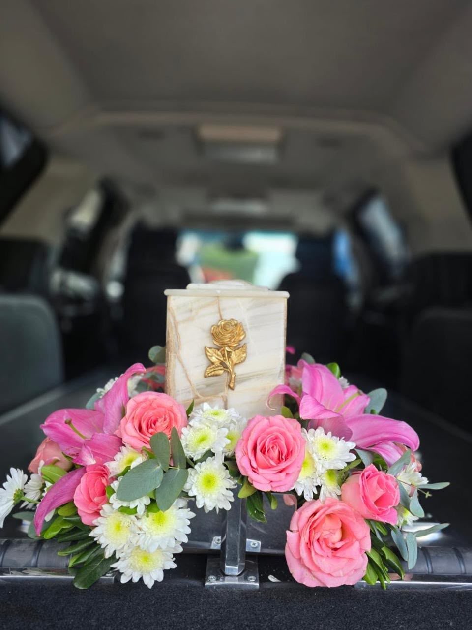 Urna funeraria decorada con arreglo floral en tonos rosas