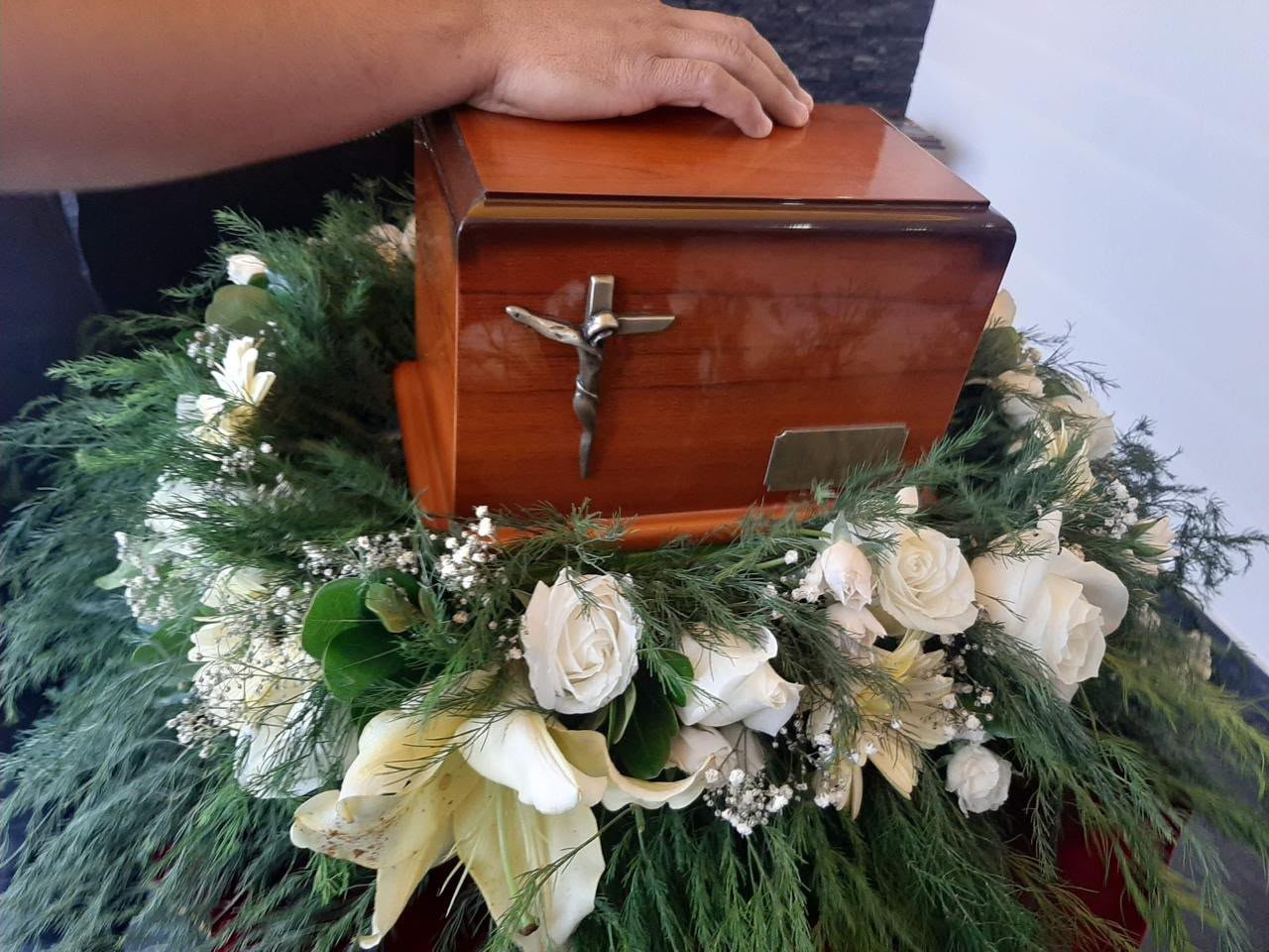 Urna funeraria con crucifijo y arreglo floral, representando los planes de previsión de Funerales VidaNueva